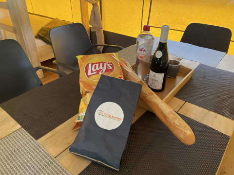 Mesa en una tienda safari en Camping le Mas de Mourgues, Francia, con vino, pan, agua y patatas fritas.