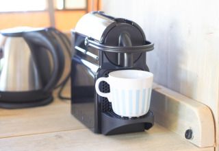 Nespresso-koffiezet met kopje en waterkoker op het aanrecht in een safaritent-keuken.