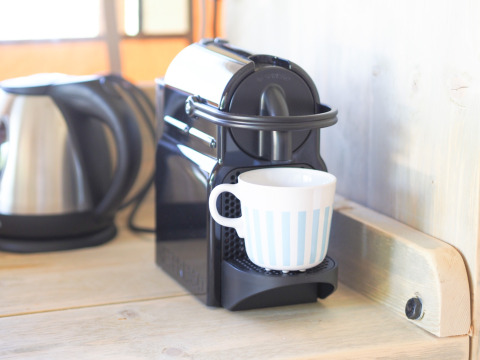Máquina de café Nespresso con taza y hervidor de agua en la encimera de una cocina en tienda safari.