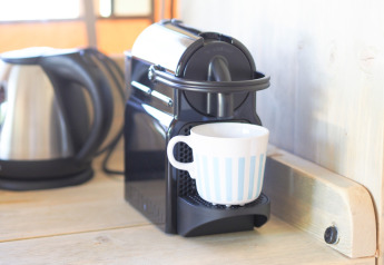 Nespresso-Kaffeemaschine mit Tasse und Wasserkocher auf der Arbeitsplatte eines Safarizeltes.
