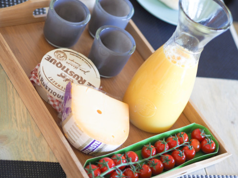 Frühstückstablett mit Saft, Tomaten, Käse, Camembert und drei blauen Tassen im Safarizelt.