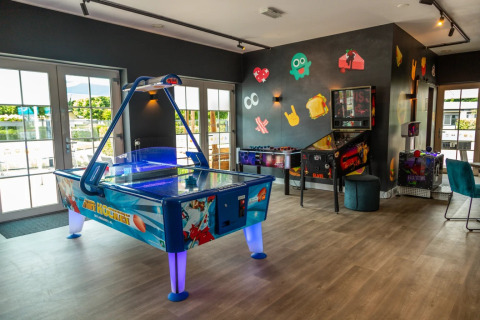 Salle de jeux dans un parc de vacances glamping, avec air hockey, baby-foot et flipper à l'intérieur.