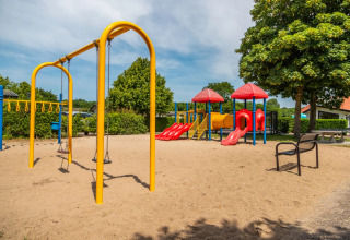Speeltuin met schommels en glijbanen in een vakantiepark met glampingmogelijkheden op een zonnige dag