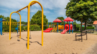 Parque infantil con columpios y toboganes en un parque vacacional con alojamientos glamping, día soleado