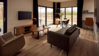 Salón moderno en la villa vacacional Amalia 2 en Hofparken Wiltershaar con ventanales y vista a la naturaleza.