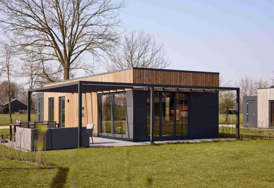 Moderne vakantie villa Amalia in Hofparken Wiltershaar, Nederland, met terras en veel groen gras.