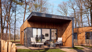Villa vacacional moderna de madera con terraza y asientos, rodeada de bosque en Hofparken Wiltershaar, Países Bajos.