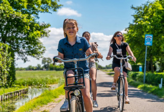 Drei Menschen fahren an einem sonnigen Tag durch grüne Landschaft in der Nähe eines Glamping-Parks Fahrrad.