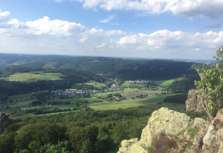 Udsigt over grønne marker, skove og landsbyer nær Brilon i Nordrhein-Westfalen, Tyskland, under blå himmel.