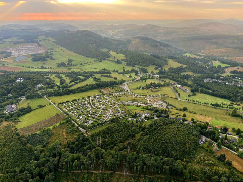Luchtfoto van Camping & Ferienpark Brilon in het heuvelachtige landschap van Noordrijn-Westfalen, Duitsland bij zonsondergang.