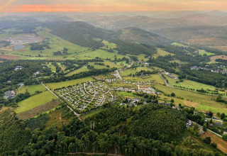 Aerial view of Camping & Ferienpark Brilon surrounded by scenic hills and fields in North Rhine-Westphalia, Germany.