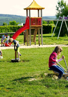 Children playing on a playground with slide and swings at Camping & Ferienpark Brilon in North Rhine-Westphalia, Germany.