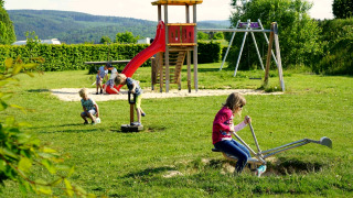 Children playing on a playground with slide and swings at Camping & Ferienpark Brilon in North Rhine-Westphalia, Germany.