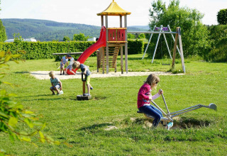 Kinderen spelen op een speelplein met glijbaan en schommels bij Camping & Ferienpark Brilon, Noordrijn-Westfalen.