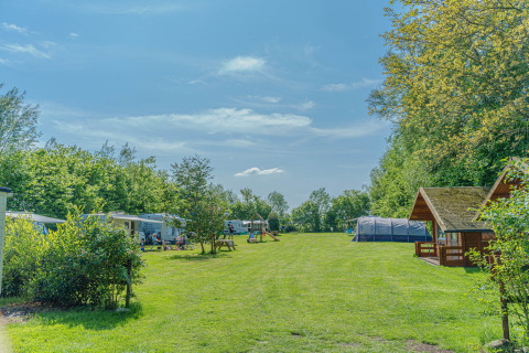 Camping avec pelouse, arbres, tentes et cabanes au Mini Camping Drentse Monden, Drenthe, Pays-Bas.