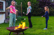 Børn rister skumfiduser over et bål på græsset i Mini Camping Drentse Monden i Drenthe, Holland.
