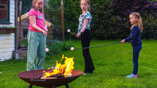 Niños asan malvaviscos sobre una fogata en Mini Camping Drentse Monden, un parque vacacional en Drenthe, Países Bajos.