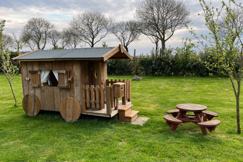 Kleines Holzhaus und Picknicktisch auf der Wiese im Mini Camping Drentse Monden, Drenthe, Niederlande.