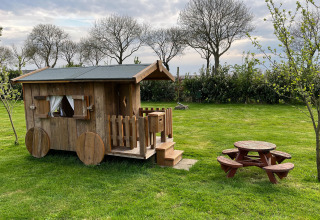 Kleines Holzhaus und Picknicktisch auf der Wiese im Mini Camping Drentse Monden, Drenthe, Niederlande.