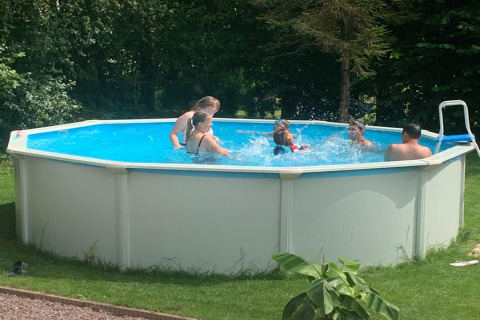 Kinder und Erwachsene plantschen gemeinsam im runden Aufstellpool des Mini Camping Drentse Monden.