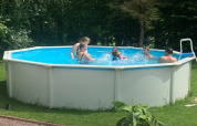 Børn og voksne nyder en sommerdag i en rund, hævet swimmingpool ved Mini Camping Drentse Monden.