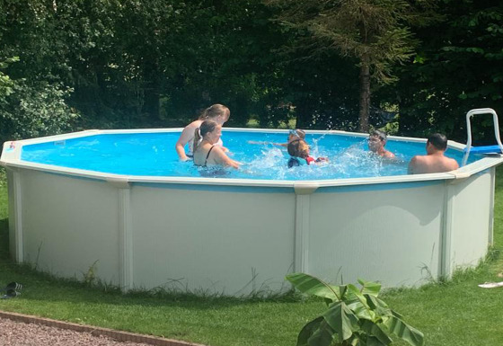 Kinderen en volwassenen genieten van zwemmen in een rond opzetzwembad bij Mini Camping Drentse Monden.