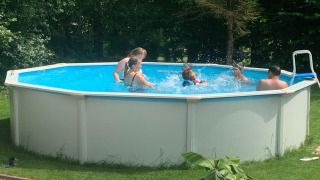 Niños y adultos se divierten nadando en una piscina redonda en Mini Camping Drentse Monden en Drenthe, Países Bajos.