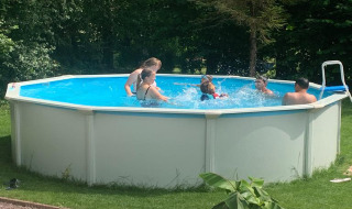 Niños y adultos se divierten nadando en una piscina redonda en Mini Camping Drentse Monden en Drenthe, Países Bajos.