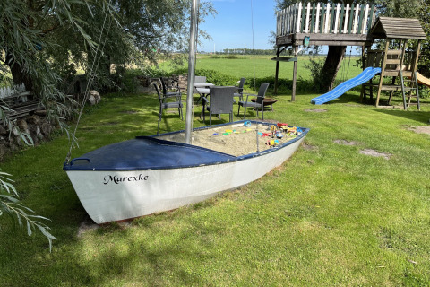 Ein Boots-Sandkasten mit Spielzeug im Garten von Mini Camping Drentse Monden, Drenthe, Niederlande.
