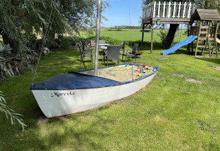 Een zandbak in de vorm van een boot met speelgoed bij Mini Camping Drentse Monden, Drenthe, Nederland.