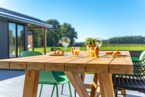 Mesa de madera al aire libre con croissants, jugo y vino en Drentse Weelde, parque vacacional en Drenthe, Países Bajos.
