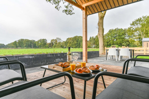 Desayuno en terraza con croissants y jugo, vista a campos verdes en Drentse Weelde, Drenthe, Países Bajos.