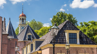 Historisch gebouw met kloktoren bij vakantiepark Drentse Weelde in Drenthe, Nederland onder blauwe lucht.