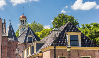 Edificio histórico y torre del reloj bajo cielo azul en el parque vacacional Drentse Weelde, Drenthe, Países Bajos.