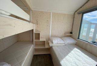 Bright beach house interior with bunk bed, double bed and window view of the sea in Dishoek, Zeeland.