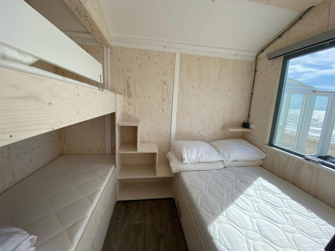Bright beach house interior with bunk bed, double bed and window view of the sea in Dishoek, Zeeland.