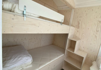 Literas de madera clara con colchones y ropa de cama blanca en una moderna cabaña en Dishoek, Zeeland, Países Bajos.