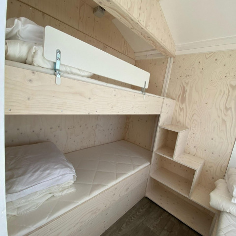Lichte houten stapelbedden met witte matrassen en beddengoed in een moderne cabin in Dishoek, Zeeland.