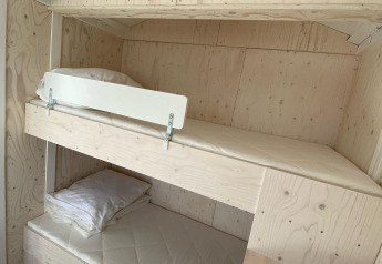 Et lyst værelse i hytten Beach house 'Dishoek 345/346' med køjesenge og minimalistisk træinteriør.