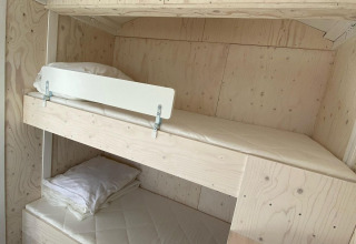 Et lyst værelse i hytten Beach house 'Dishoek 345/346' med køjesenge og minimalistisk træinteriør.