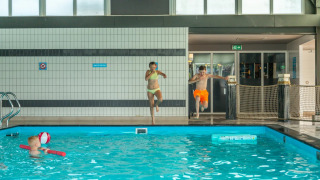Bambini saltano in una piscina al coperto in un parco vacanze che offre sistemazioni glamping.