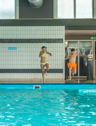Niños saltan a una piscina cubierta en un parque vacacional con alojamiento glamping, jugando juntos.