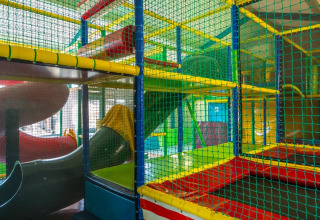 Indoor speeltuin met kleurrijke buizen en netten in een vakantiepark met glamping accommodaties.