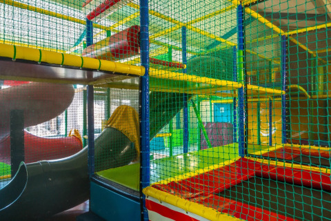 Aire de jeux intérieure colorée avec toboggans, située dans un parc de vacances proposant du glamping.