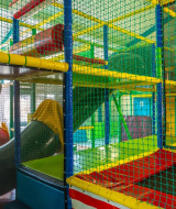 Parque infantil interior con tubos y redes coloridas en un parque vacacional con glamping.