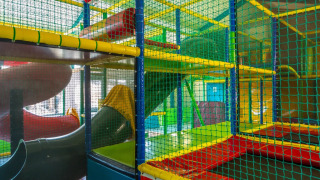 Parco giochi al coperto con tubi e reti colorate in un villaggio turistico che offre il glamping.