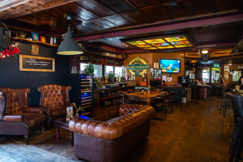 Area lounge accogliente con divani in pelle e bar in un glamping di un parco vacanze, decorazioni in legno.