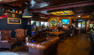 Acogedora sala de estar con sofás de cuero y bar en un glamping de parque vacacional, decoración rústica.