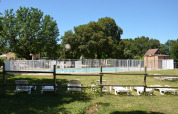 Udendørs swimmingpool med hvidt hegn, liggestole og grønt græs på Camping le Roc, Occitanie, Frankrig.