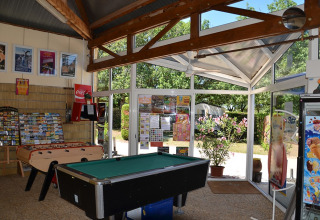 Gemeenschappelijke ruimte in Camping le Roc met kicker, pooltafel, affiches en tuinzicht in Occitanië.